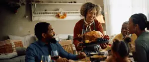 Happy grandmother bringing roast turkey to dining table
